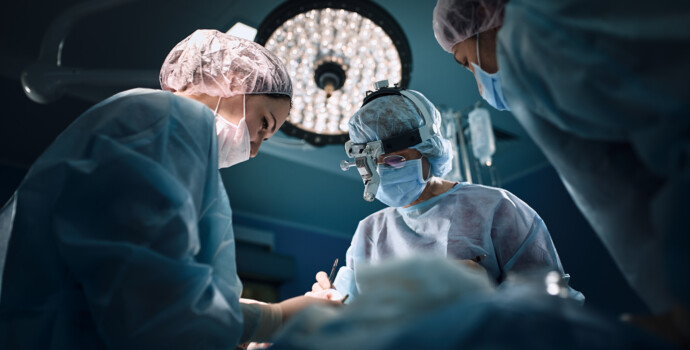 Medical team in the operating room, dark background. The theater of the operating room, an international team of professional doctors in a modern operating room are conducting an operation. Saving lives, modern medicine, blue blue light