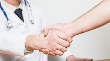 middle aged doctor with gray hair and beard making handshake