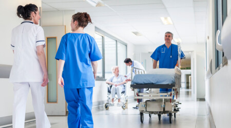 Male nurse pushing stretcher gurney bed in hospital corridor wit