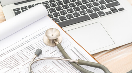 Stetoscopio appoggiato su un modulo accanto a un computer portatile