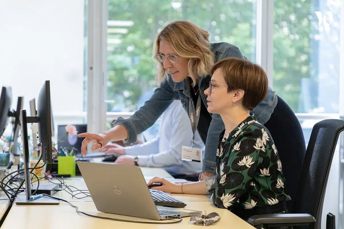 Deux collaboratrices échangeant et travaillant ensemble devant un ordinateur portable.
