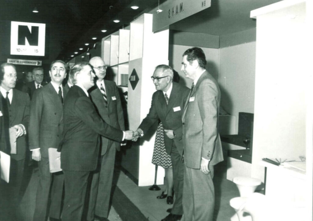 Führungskräfte im Anzug begrüßen sich bei einer institutionellen Veranstaltung.