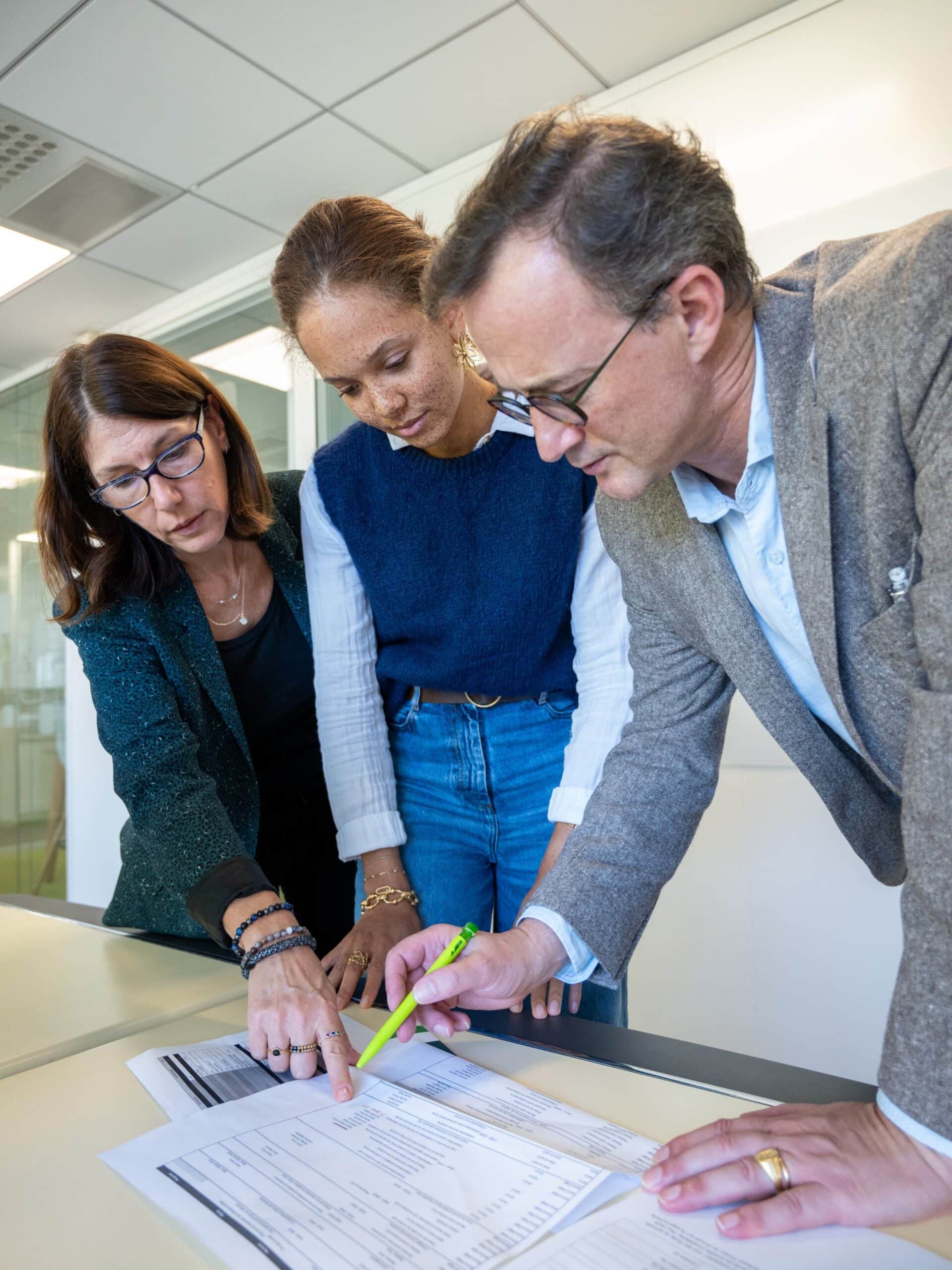 Trois collègues analysant des documents sur un bureau