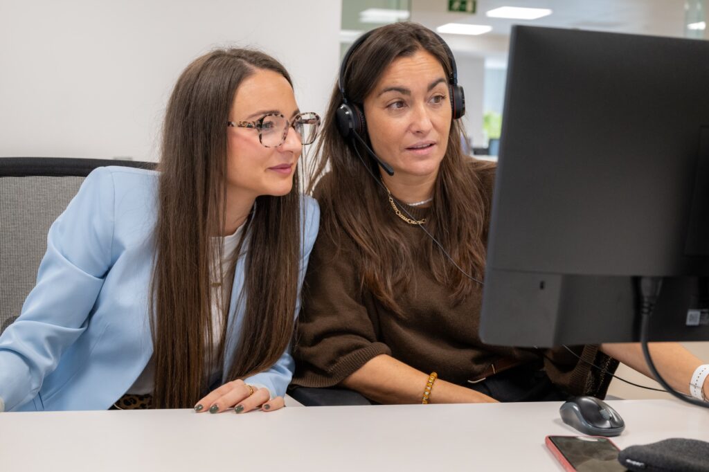 Deux collaboratrices assises devant un ordinateur, concentrées sur l’écran
