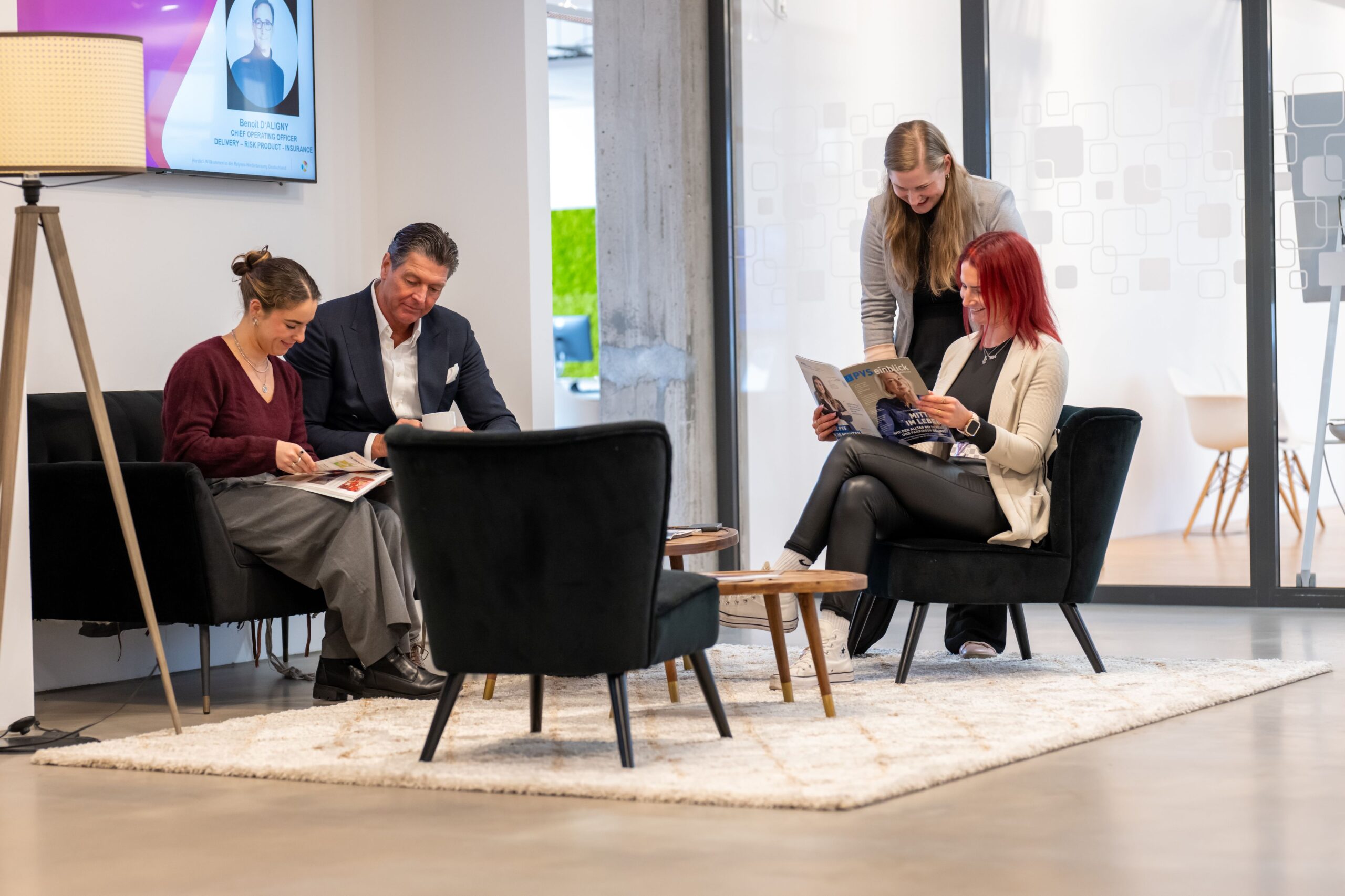 Mitarbeitende sitzen in einem Loungebereich und lesen gemeinsam Magazine.