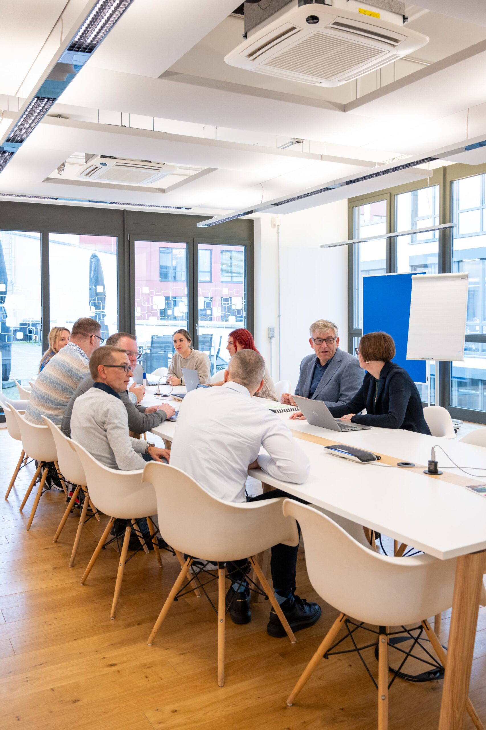 Mitarbeitende sitzen in einem Besprechungsraum zu einer gemeinsamen Arbeitsrunde zusammen.