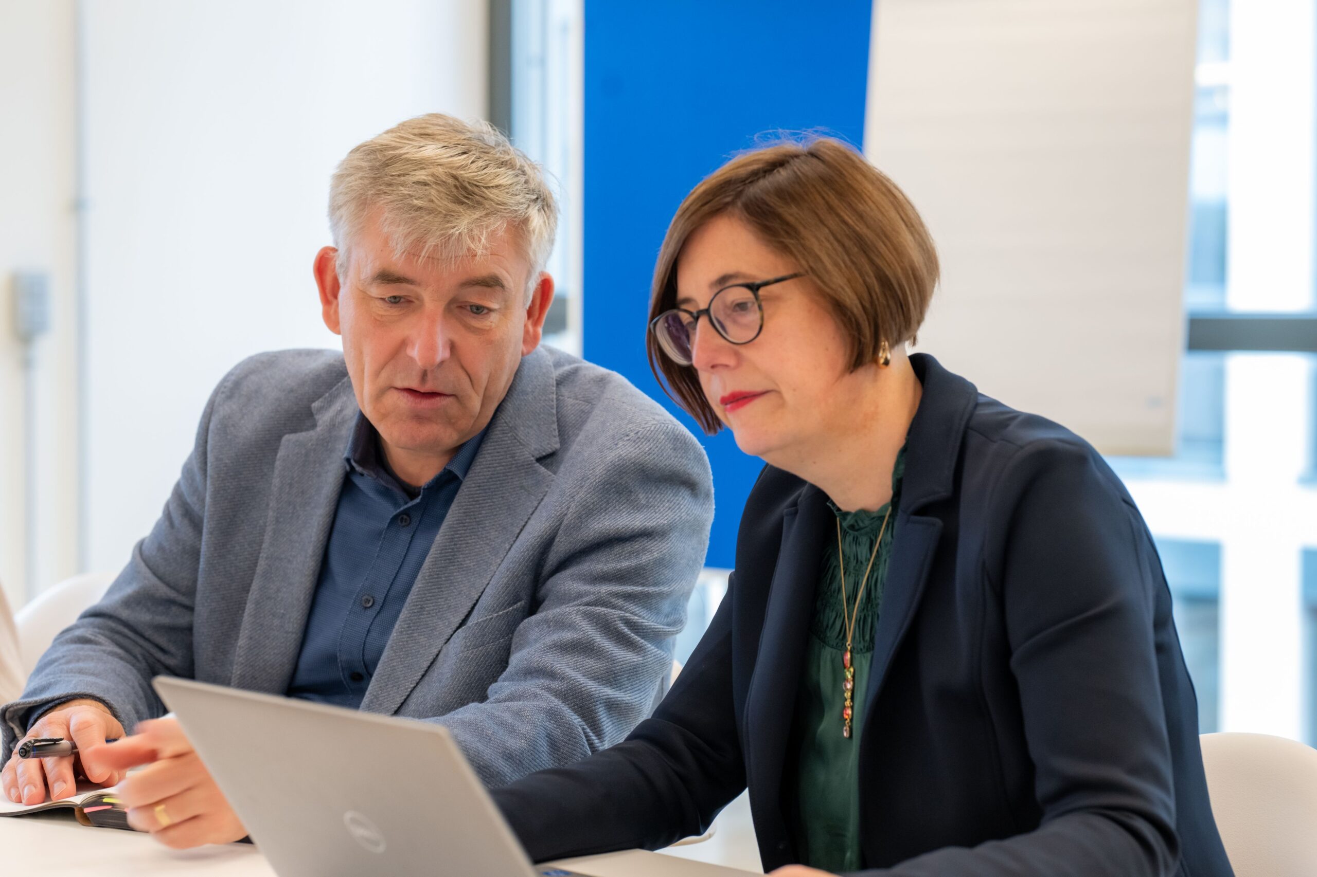 Zwei Mitarbeitende arbeiten gemeinsam an einem Laptop.