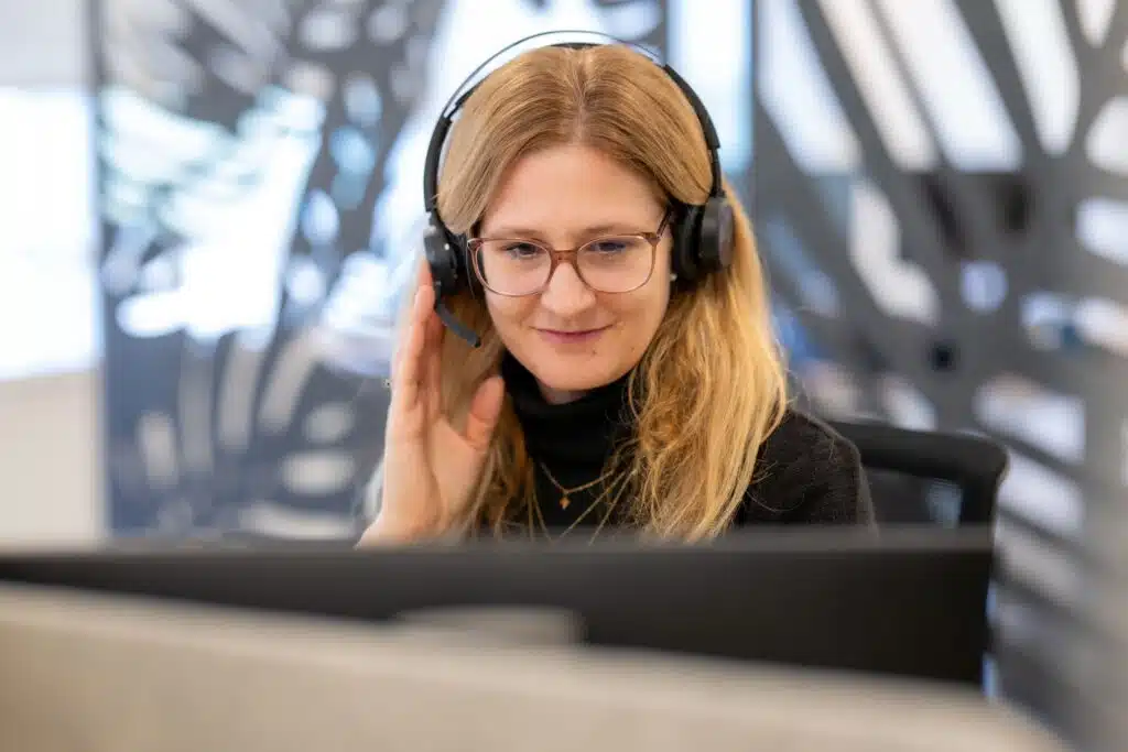 Colaboradora con auriculares frente a un ordenador