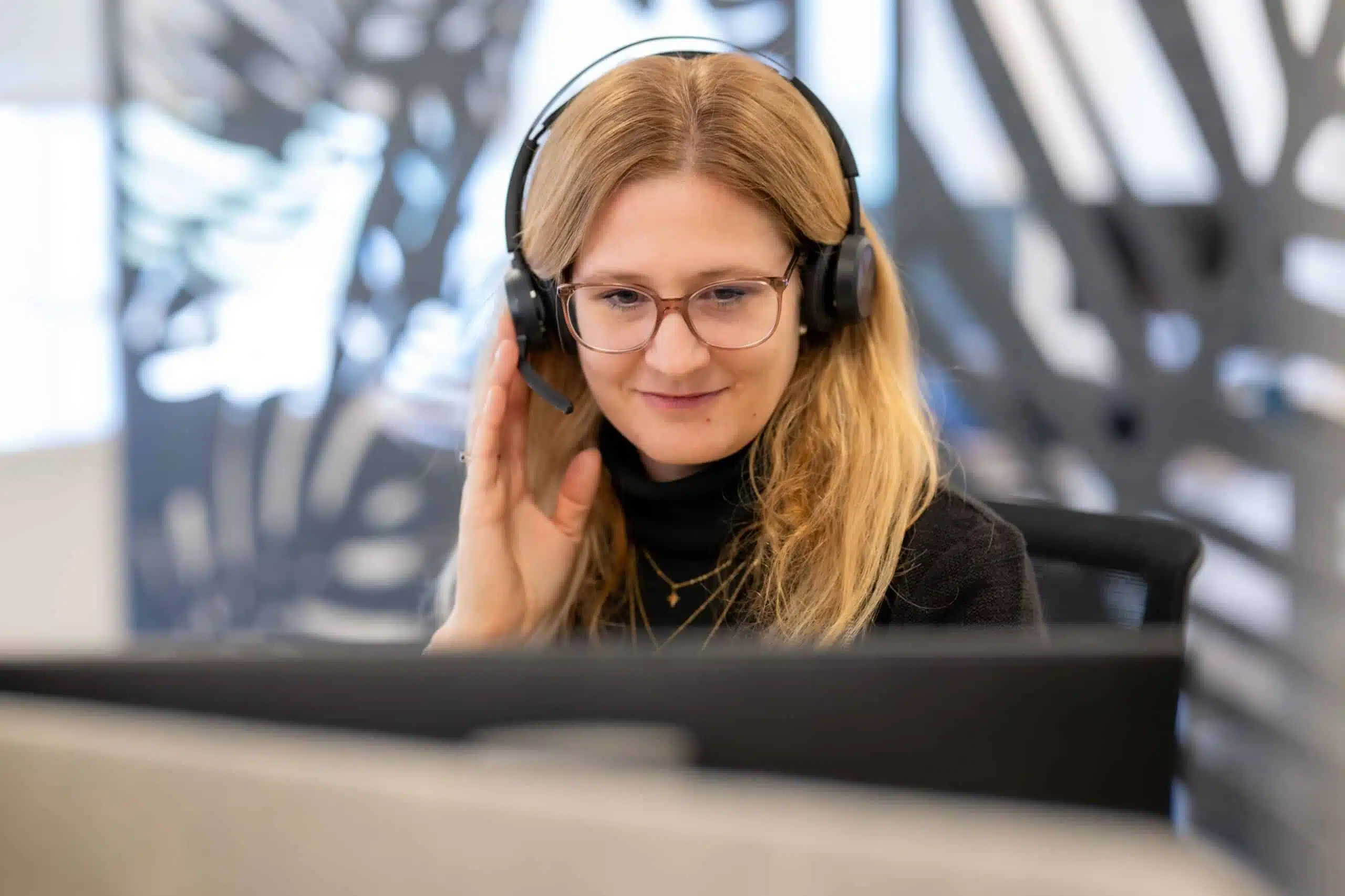 Collaboratrice avec un casque face à un ordinateur