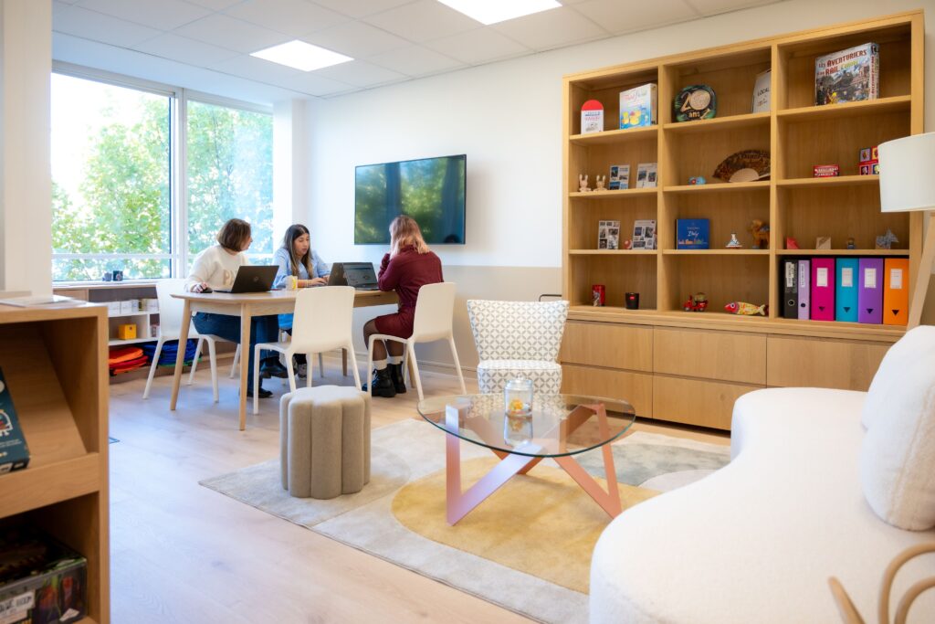 Drei Mitarbeiterinnen, die gemeinsam an einem Tisch in einem gemütlichen Raum arbeiten