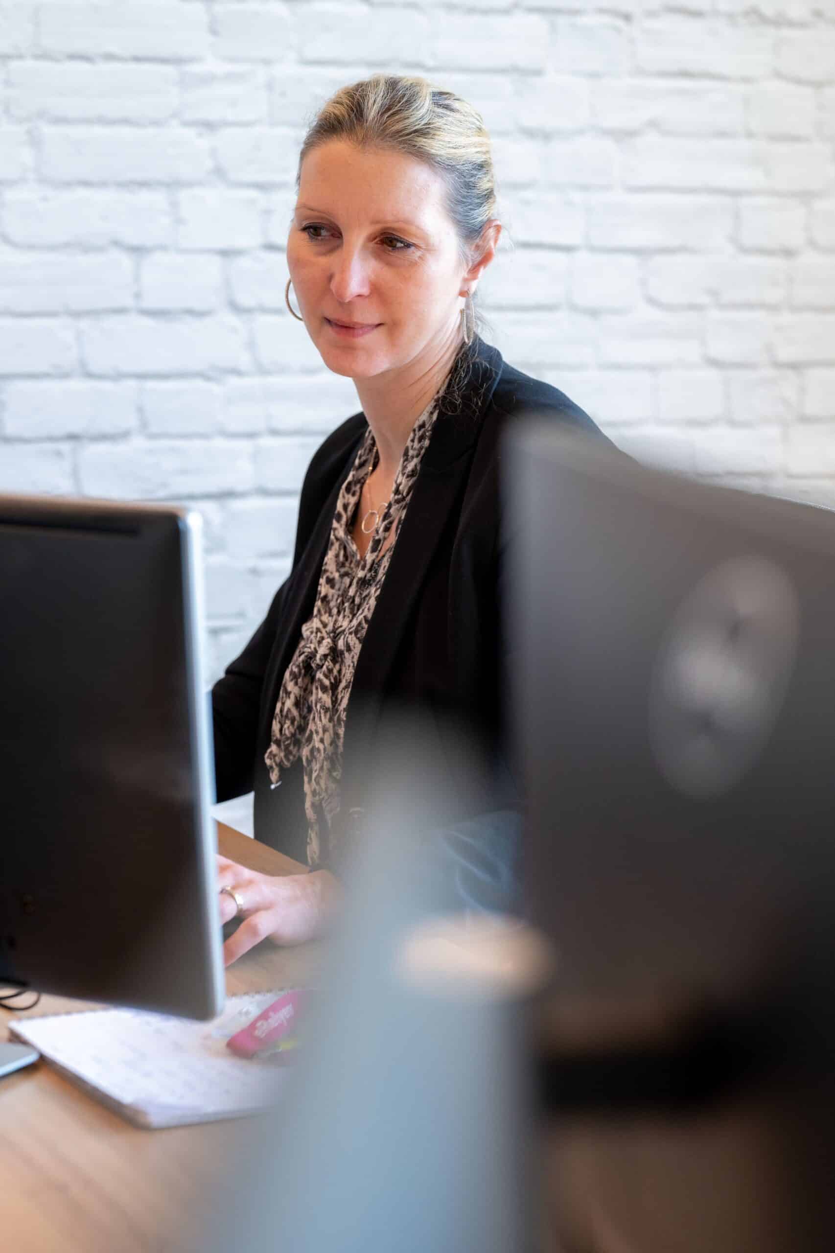 Una donna con i capelli biondi legati, che indossa un blazer nero e una sciarpa fantasia