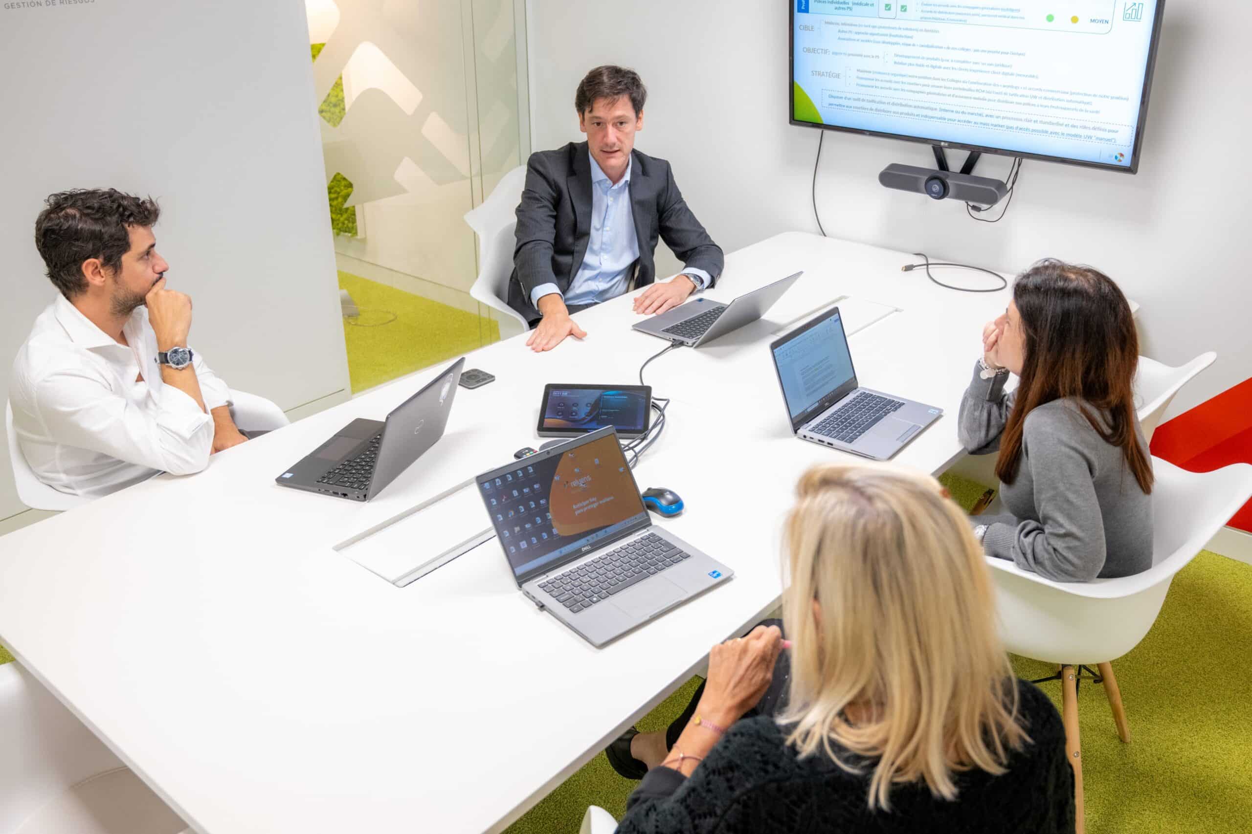 Reunión de trabajo entre varios colaboradores alrededor de una mesa con ordenadores portátiles.