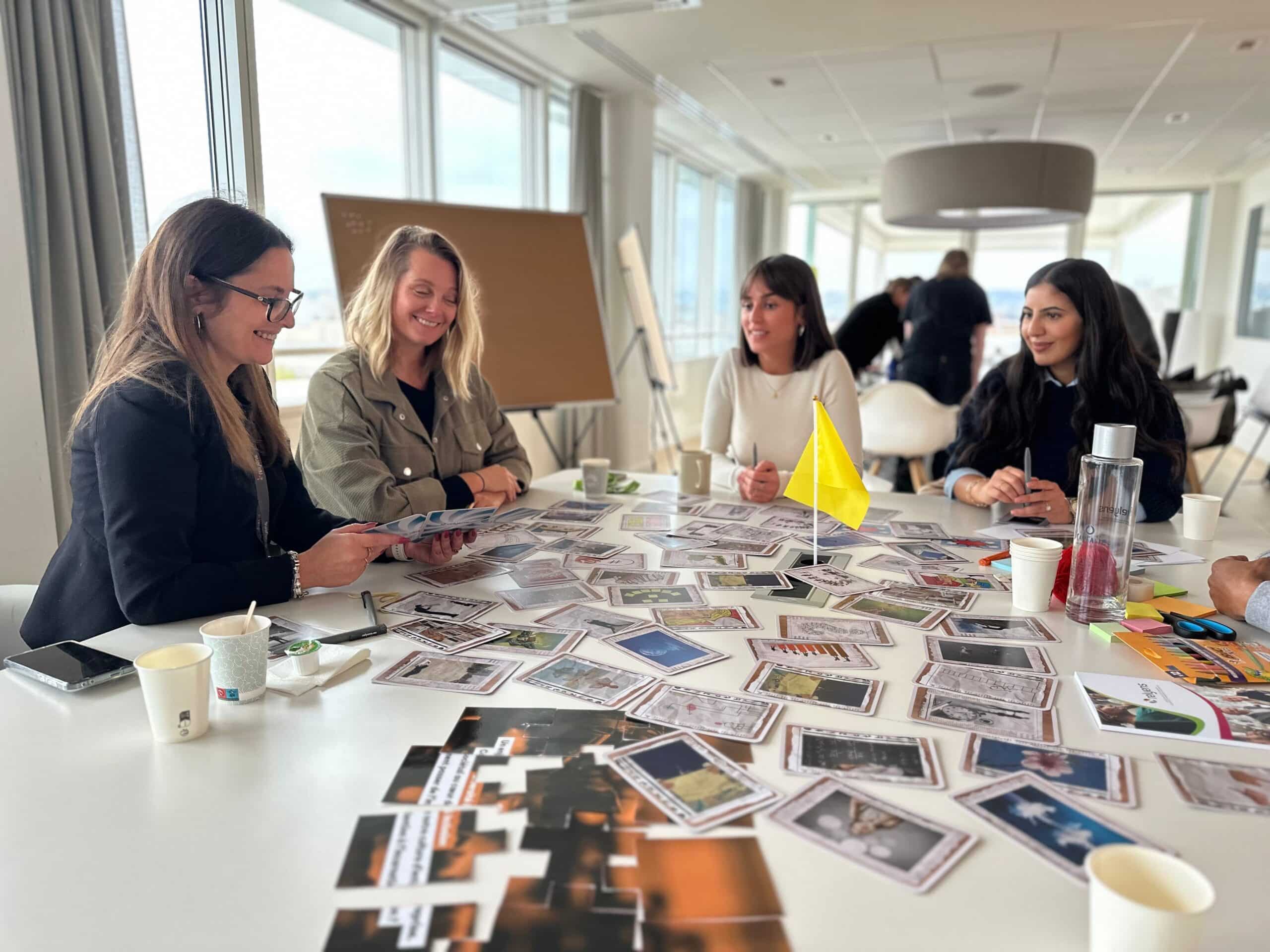 Atelier collaboratif avec plusieurs participantes échangeant autour de cartes étalées sur une table.