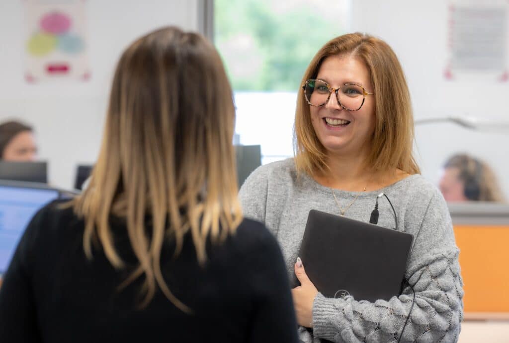 Collaboratrice souriante échangeant avec une collègue