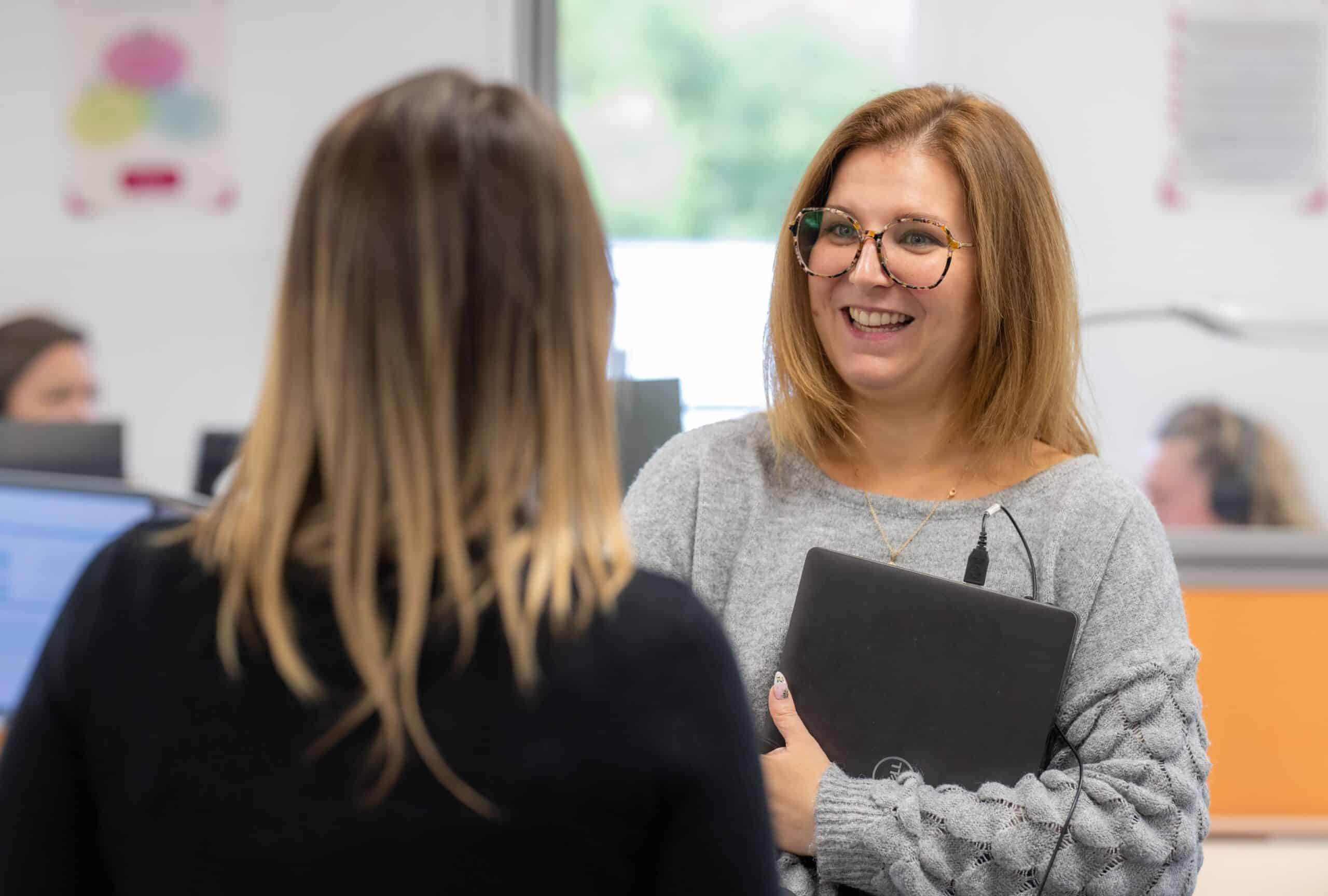 Colaboradora sonriente conversando con una compañera.